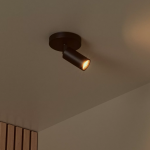 Zwarte moderne plafondspot met warme lichtstraal in minimalistisch interieur