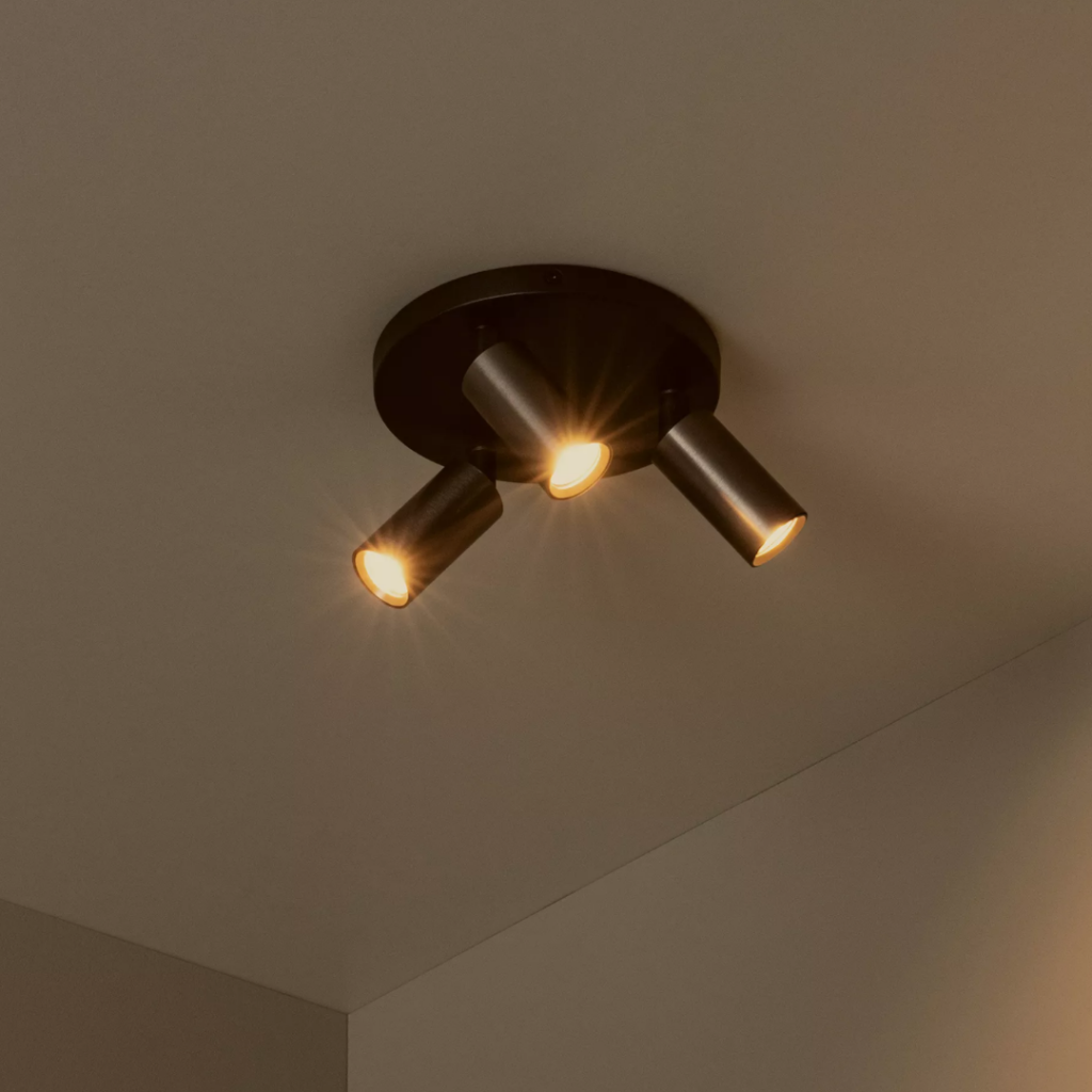 Moderne drievoudige plafondspot in koffiekleur met warme lichtbundels aan plafond