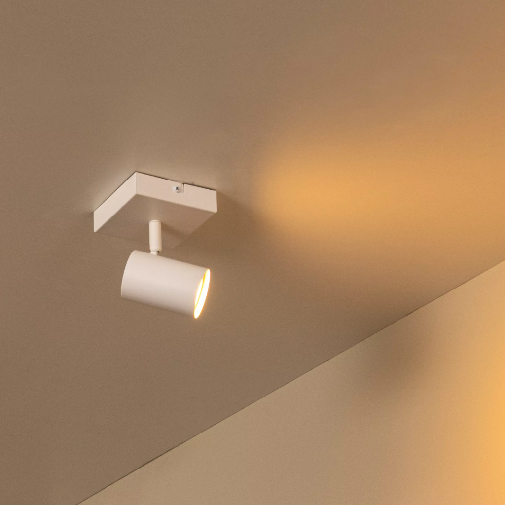 Witte metalen plafondlamp met één spot en warm licht in moderne kamer
