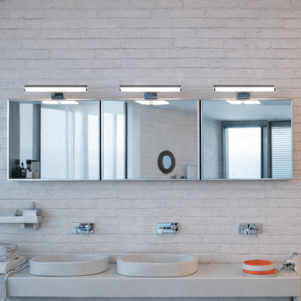 Zwarte moderne spiegellamp boven badkamerspiegel met helder wit licht in moderne badkamer