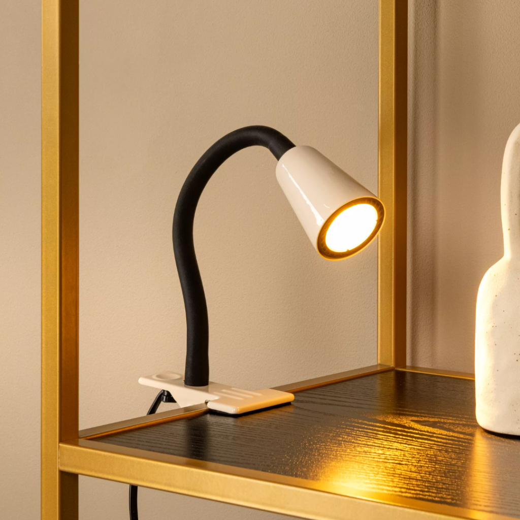 Beige klemlamp met flexibele zwarte arm verlicht houten plank in interieur
