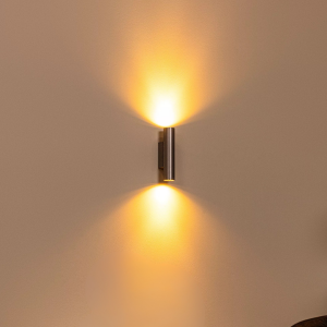 Grijze metalen wandlamp met warm up en down lichteffect tegen muur