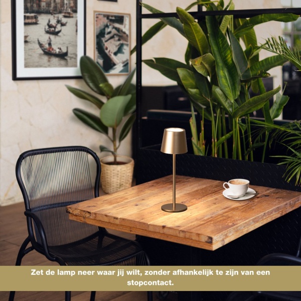 4052231504990_sfeerbeeld_010 Oplaadbare koffiekleurige tafellamp met warme lichttoon op houten tafel in cafésetting