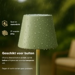 Groene oplaadbare tafellamp buiten in de regen op terras