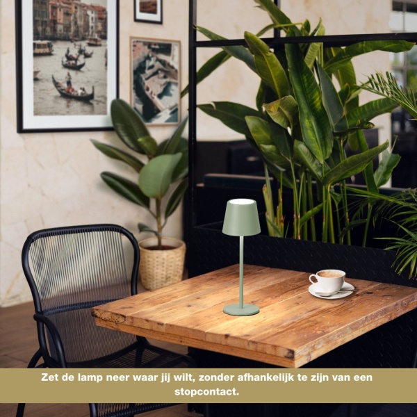 Oplaadbare saliegroene tafellamp met warm licht op houten tafel in cafésetting
