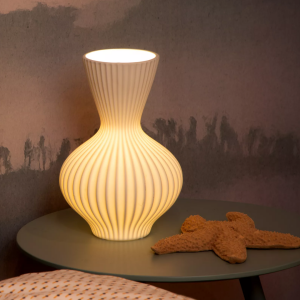 Witte ribbelvormige tafellamp met warm licht op nachtkastje