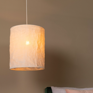 Witte hanglamp van textiel met warme gloed boven bed in slaapkamer