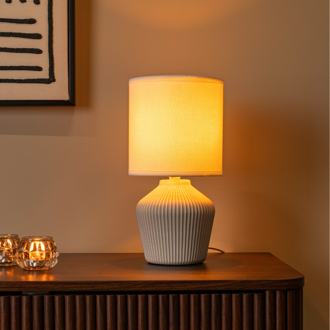 FILIZ Beige keramische tafellamp met geribde voet en warme lichtgloed op dressoir