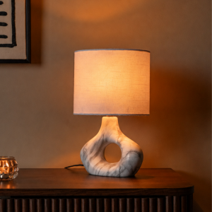 Tafellamp met marmeren voet en beige kap op houten dressoir